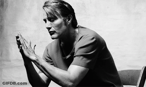 A Black And White Photo Of A Man Sitting In A Chair With His Hands Folded In Prayer . GIF