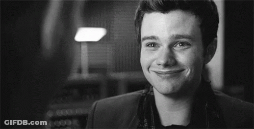 A Black And White Photo Of A Man Smiling In A Room . GIF