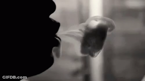 A Black And White Photo Of A Man Smoking A Cigarette . GIF