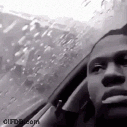 A Black And White Photo Of A Man Smoking A Cigarette While Sitting In A Car . GIF
