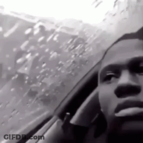 A Black And White Photo Of A Man Smoking A Cigarette While Sitting In A Car . GIF