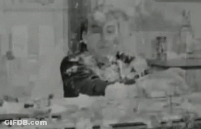 A Black And White Photo Of A Man Standing In A Room Covered In Paint . GIF