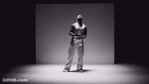 A Black And White Photo Of A Man Standing In Front Of A Cardboard Box GIF