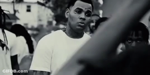 A Black And White Photo Of A Man Standing In Front Of A Crowd Of People . GIF