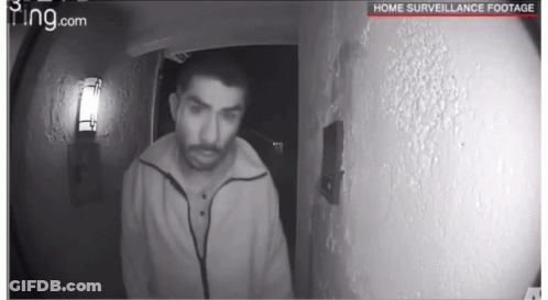 A Black And White Photo Of A Man Standing In Front Of A Door With The Words Home Surveillance Footage On The Bottom GIF