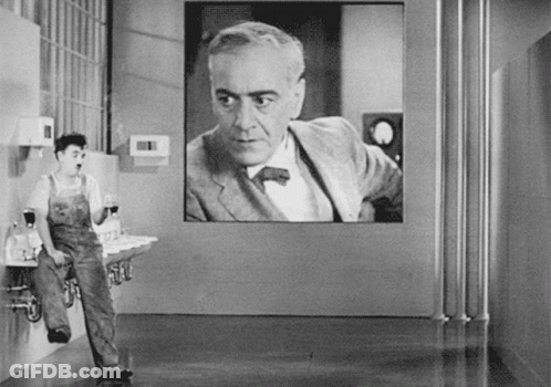 A Black And White Photo Of A Man Standing In Front Of A Large Screen GIF
