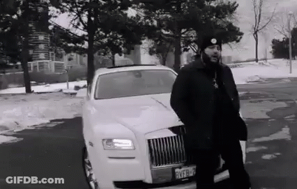 A Black And White Photo Of A Man Standing Next To A White Limousine In A Parking Lot . GIF