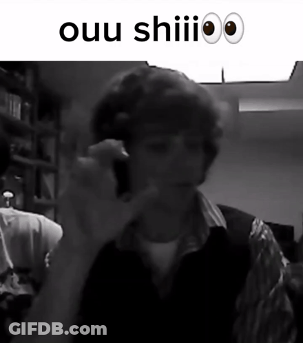A Black And White Photo Of A Man Talking On A Cell Phone With The Words Ouu Shiii Above Him GIF