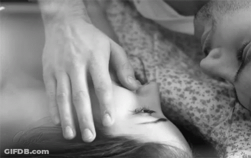 A Black And White Photo Of A Man Touching A Woman 'S Face While Laying On A Bed . GIF