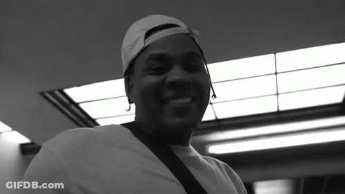 A Black And White Photo Of A Man Wearing A Baseball Cap And Smiling GIF