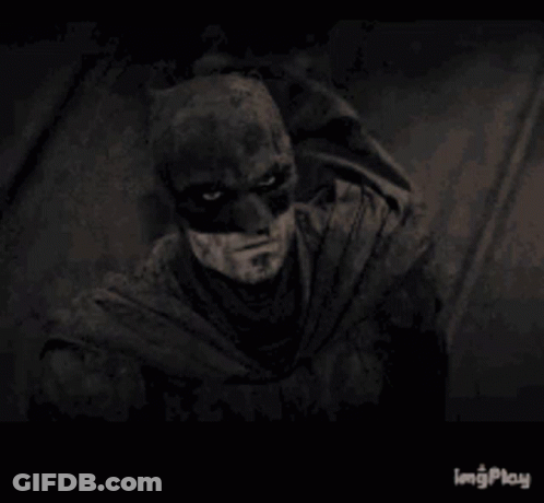 A Black And White Photo Of A Man Wearing A Batman Mask . GIF