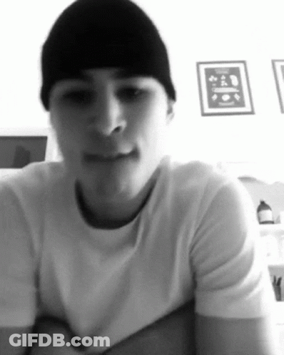 A Black And White Photo Of A Man Wearing A Beanie And A White T-Shirt GIF