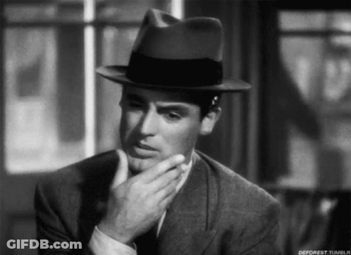 A Black And White Photo Of A Man Wearing A Fedora Hat GIF