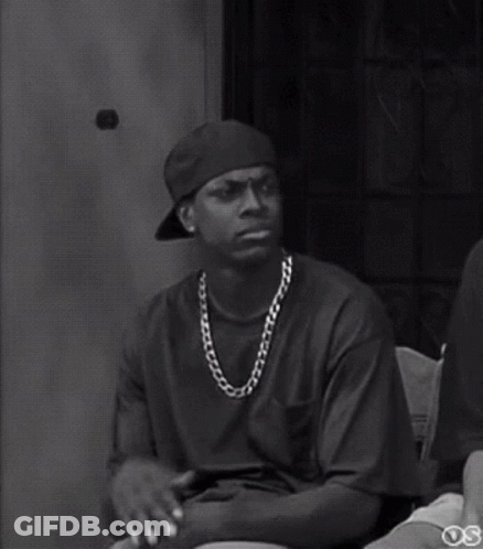 A Black And White Photo Of A Man Wearing A Hat And A Chain Around His Neck . GIF