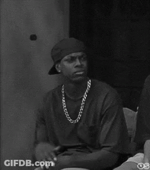A Black And White Photo Of A Man Wearing A Hat And A Chain Around His Neck . GIF