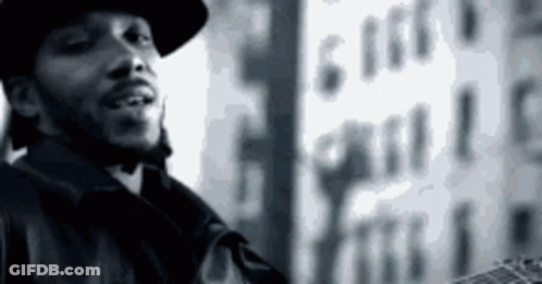 A Black And White Photo Of A Man Wearing A Hat And Holding A Guitar . GIF