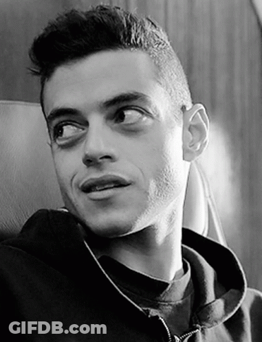 A Black And White Photo Of A Man Wearing A Hoodie Sitting In A Chair . GIF