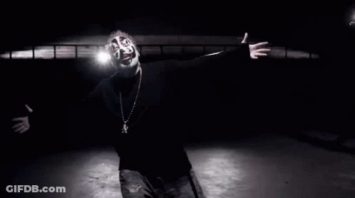 A Black And White Photo Of A Man Wearing A Mask And A Necklace GIF