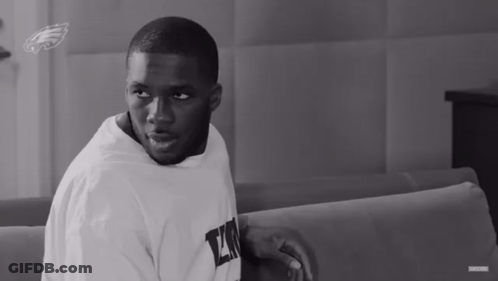 A Black And White Photo Of A Man Wearing A White Shirt With The Letter L On It GIF