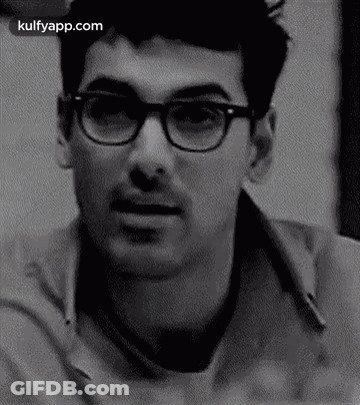 A Black And White Photo Of A Man Wearing Glasses And A Mustache . GIF