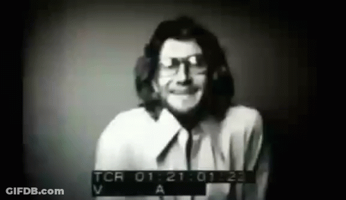 A Black And White Photo Of A Man Wearing Glasses And A White Shirt . GIF