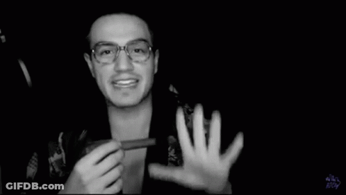 A Black And White Photo Of A Man Wearing Glasses Holding Something In His Hand . GIF