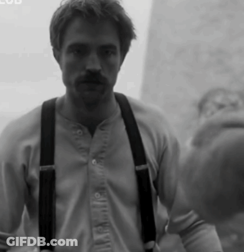 A Black And White Photo Of A Man Wearing Suspenders And A Shirt GIF