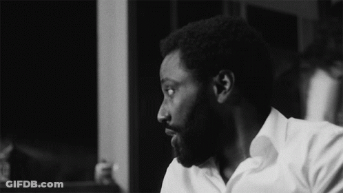 A Black And White Photo Of A Man With A Beard And A White Shirt GIF