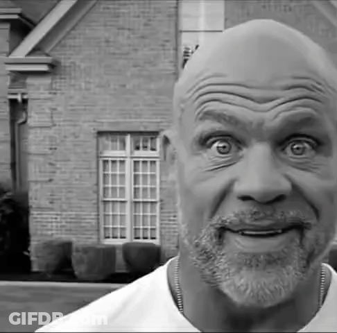 A Black And White Photo Of A Man With A Beard Making A Funny Face In Front Of A Brick House . GIF