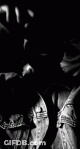 A Black And White Photo Of A Man With A Beard Wearing A Denim Jacket And Sunglasses . GIF