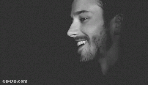 A Black And White Photo Of A Man With A Beard Wearing A Hat And Smiling . GIF