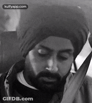 A Black And White Photo Of A Man With A Beard Wearing A Turban And Talking On A Cell Phone . GIF