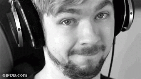 A Black And White Photo Of A Man With A Beard Wearing Headphones And Making A Funny Face . GIF