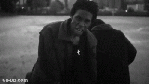 A Black And White Photo Of A Man With A Cross On His Neck . GIF