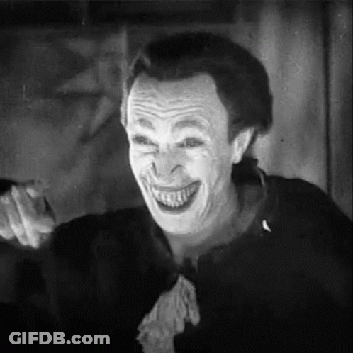 A Black And White Photo Of A Man With A Joker Mask On His Face . GIF