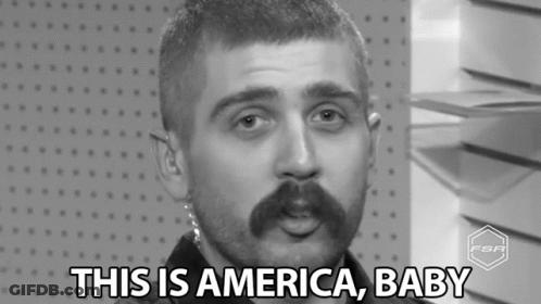 A Black And White Photo Of A Man With A Mustache Saying This Is America Baby . GIF