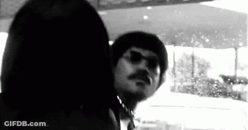 A Black And White Photo Of A Man With A Mustache Wearing Sunglasses . GIF