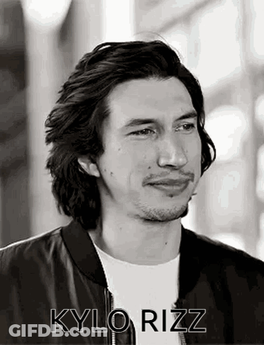 A Black And White Photo Of A Man With Long Hair And A Beard Wearing A Black Jacket . GIF