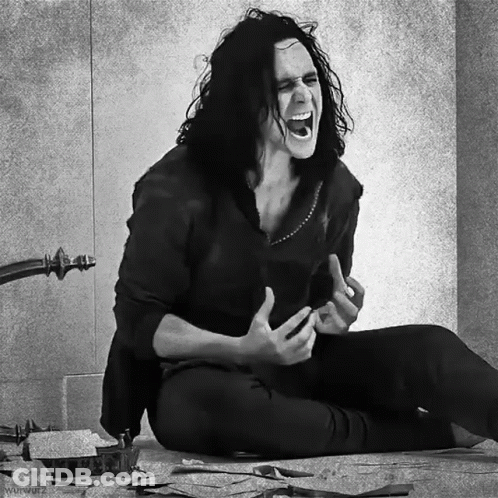 A Black And White Photo Of A Man With Long Hair Sitting On The Floor Screaming GIF