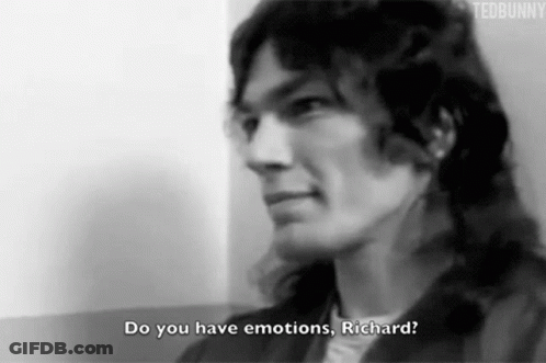 A Black And White Photo Of A Man With Long Hair Talking To Another Man . GIF