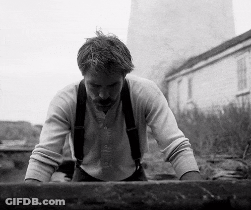 A Black And White Photo Of A Man With Suspenders Looking Down GIF
