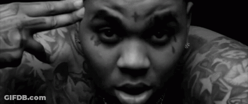 A Black And White Photo Of A Man With Tattoos On His Arms And Face . GIF