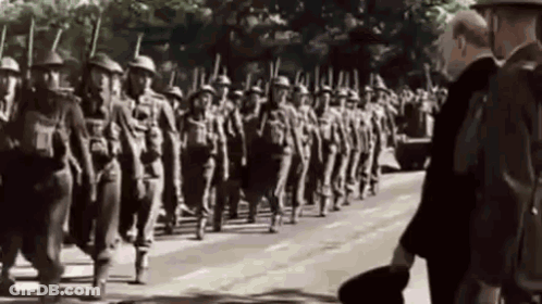 A Black And White Photo Of A Military Parade With A Man Standing In The Foreground . GIF