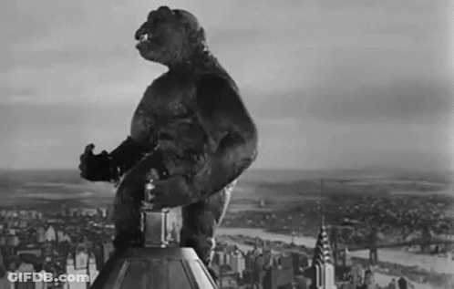 A Black And White Photo Of A Monster Standing On Top Of A Building In Front Of A City . GIF
