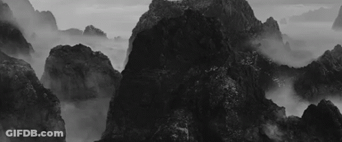 A Black And White Photo Of A Mountain Covered In Fog GIF