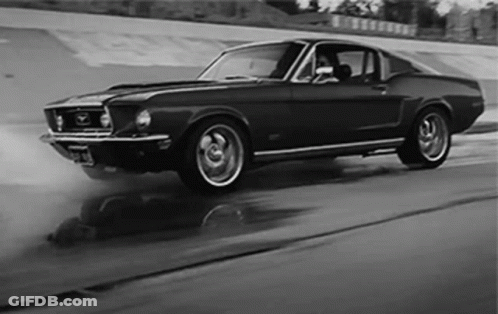 A Black And White Photo Of A Mustang Driving Down A Road GIF