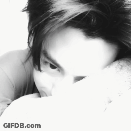 A Black And White Photo Of A Person Covering Their Face With A Pillow GIF