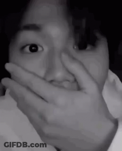 A Black And White Photo Of A Person Covering Their Mouth With Their Hand . GIF