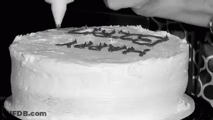 A Black And White Photo Of A Person Frosting A Cake With Icing . GIF
