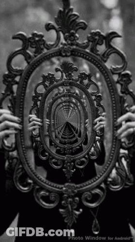 A Black And White Photo Of A Person Holding A Mirror With A Reflection Of A Tunnel In It GIF